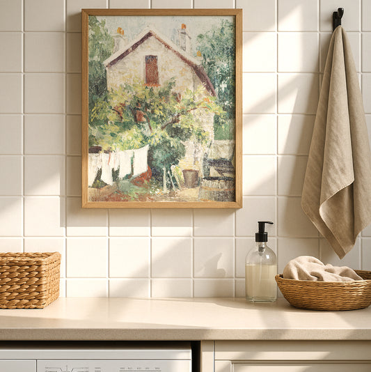 Framed vintage cottage art print featuring a stone house, lush greenery, and white laundry hanging on a clothesline in the garden.