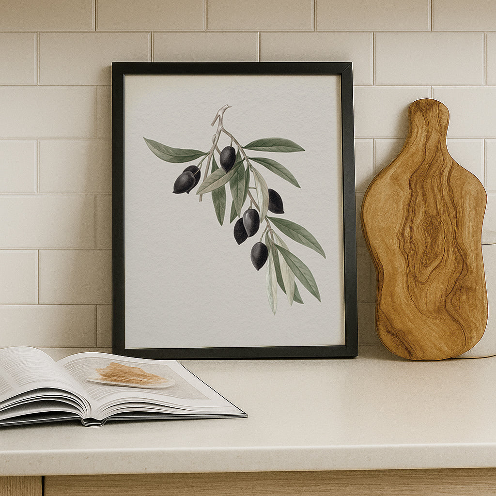 Framed artwork of an olive branch illustration on a kitchen counter with an olive tree cutting board.