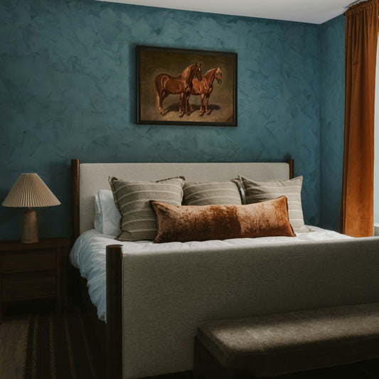 Framed vintage horses oil painting print hung above a bed on a deep teal bedroom wall, equestrian wall art, Avery Home