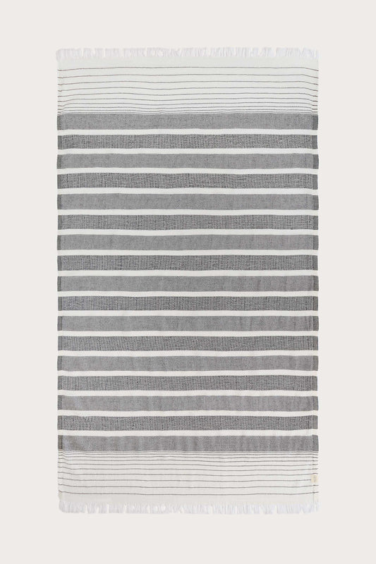 Avery Home black and white stripe peshtemal laid flat, full view of sustainable Turkish towel woven from cotton, recycled cotton and recycled polyester, with tassel fringe