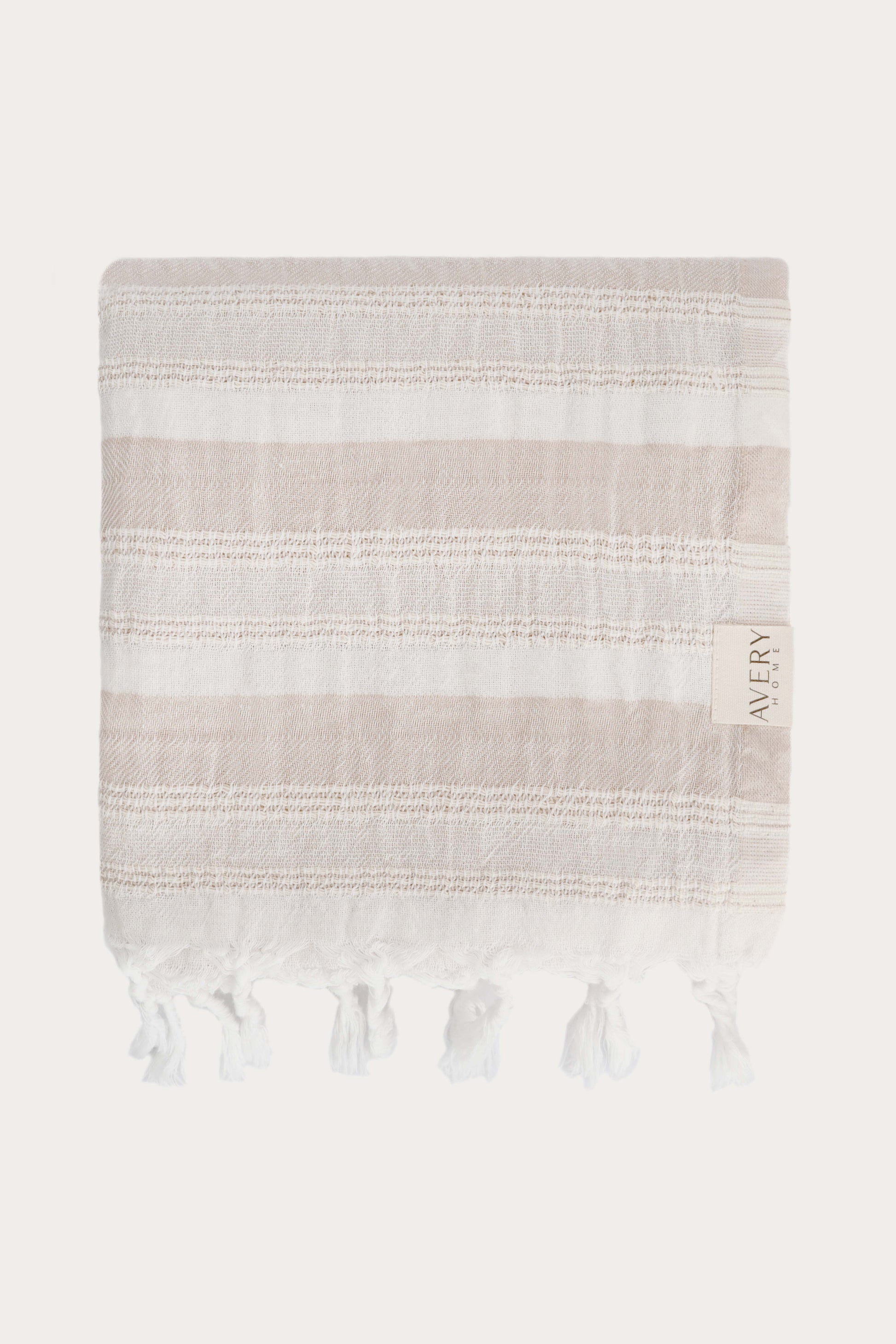 Avery Home Formentera peshtemal folded in beige and white herringbone weave luxury Turkish hammam towel with hand-knotted tassel fringe, fast-drying and lightweight