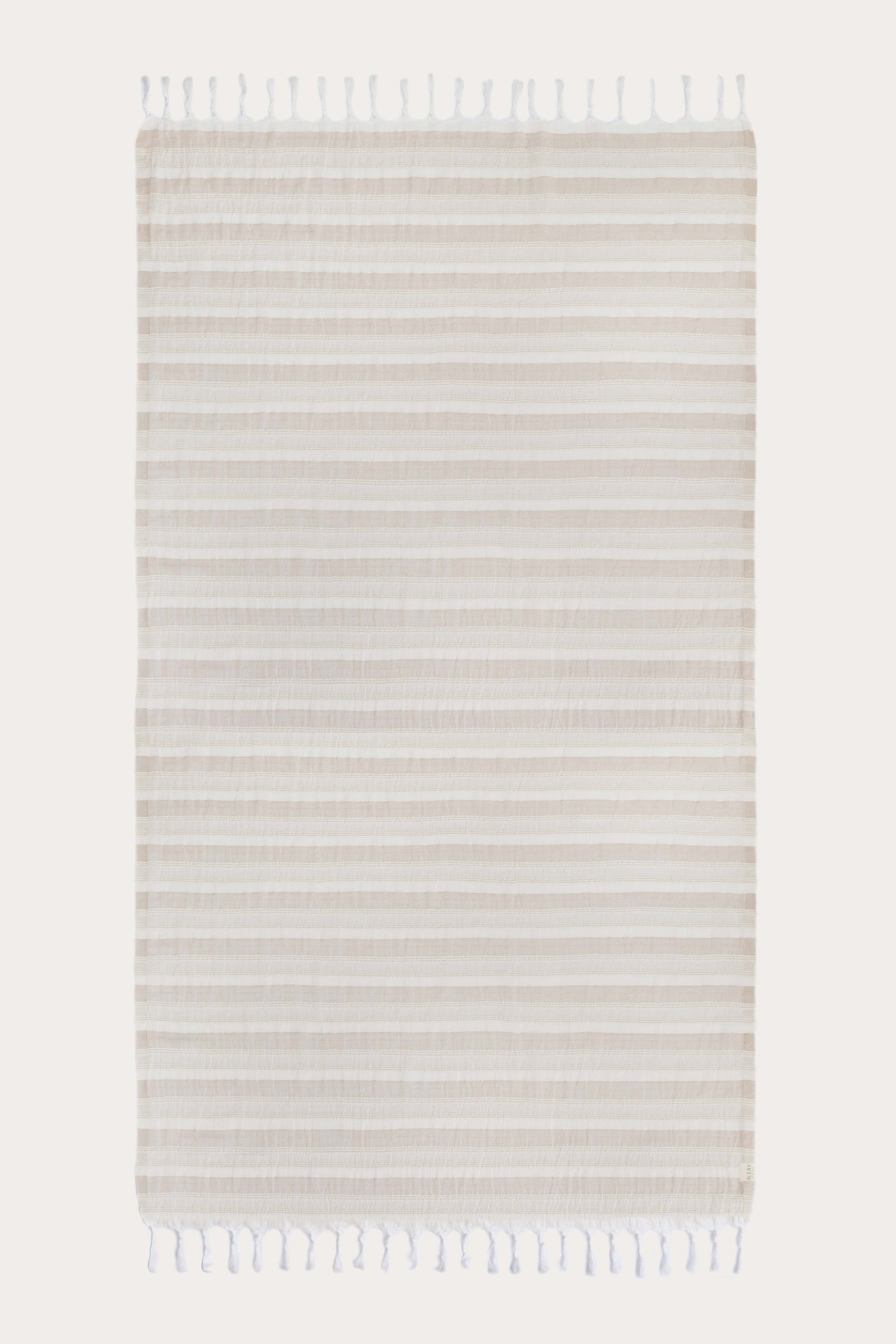 Avery Home Formentera beige and white herringbone peshtemal laid flat, full view of quick-dry Turkish cotton hammam towel with tassel fringe, for beach, spa, and bath