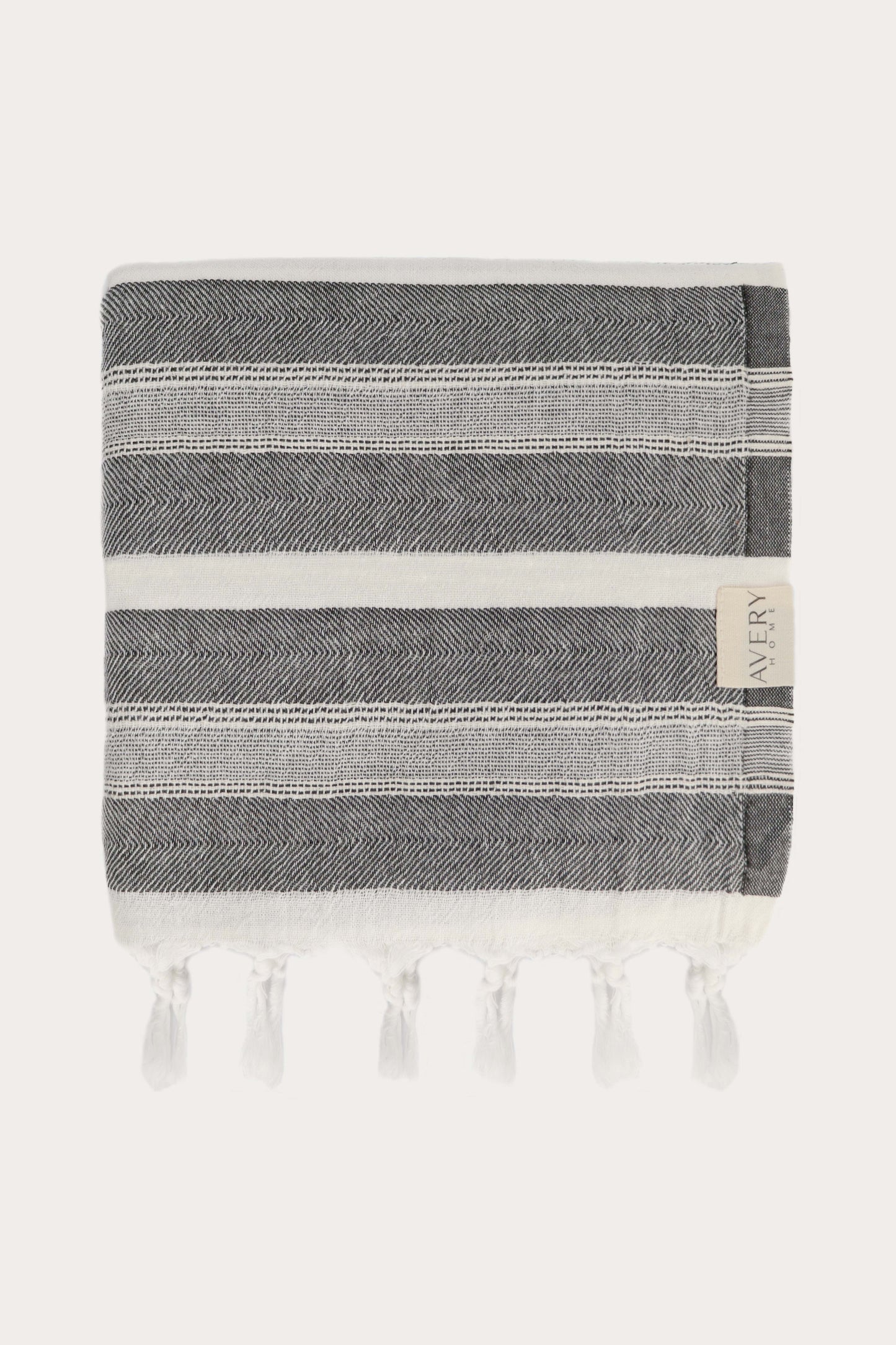 Avery Home Formentera peshtemal folded in black and white herringbone weave luxury Turkish hammam towel with hand-knotted tassel fringe, fast-drying and lightweight
