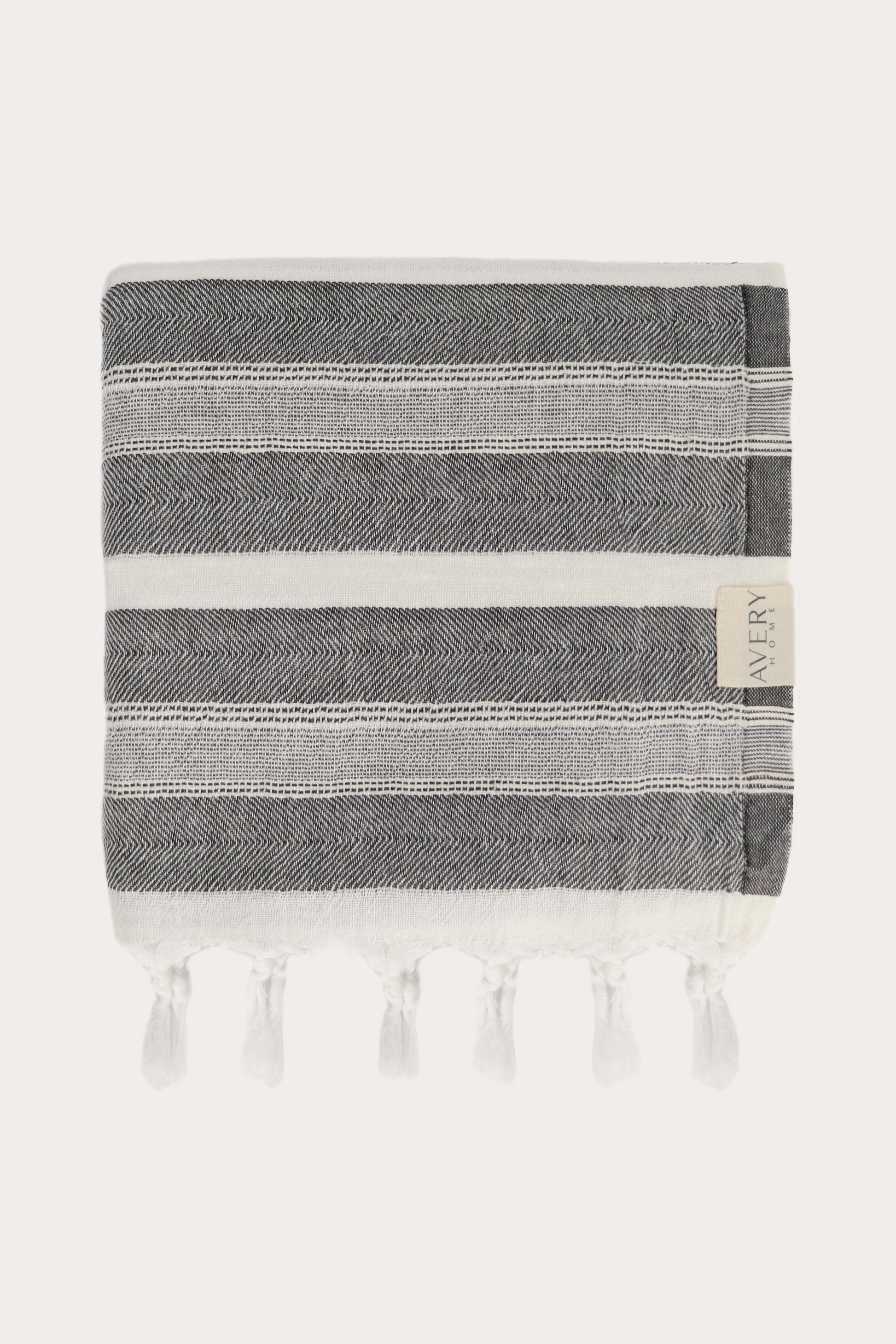 Avery Home Formentera peshtemal folded in black and white herringbone weave luxury Turkish hammam towel with hand-knotted tassel fringe, fast-drying and lightweight