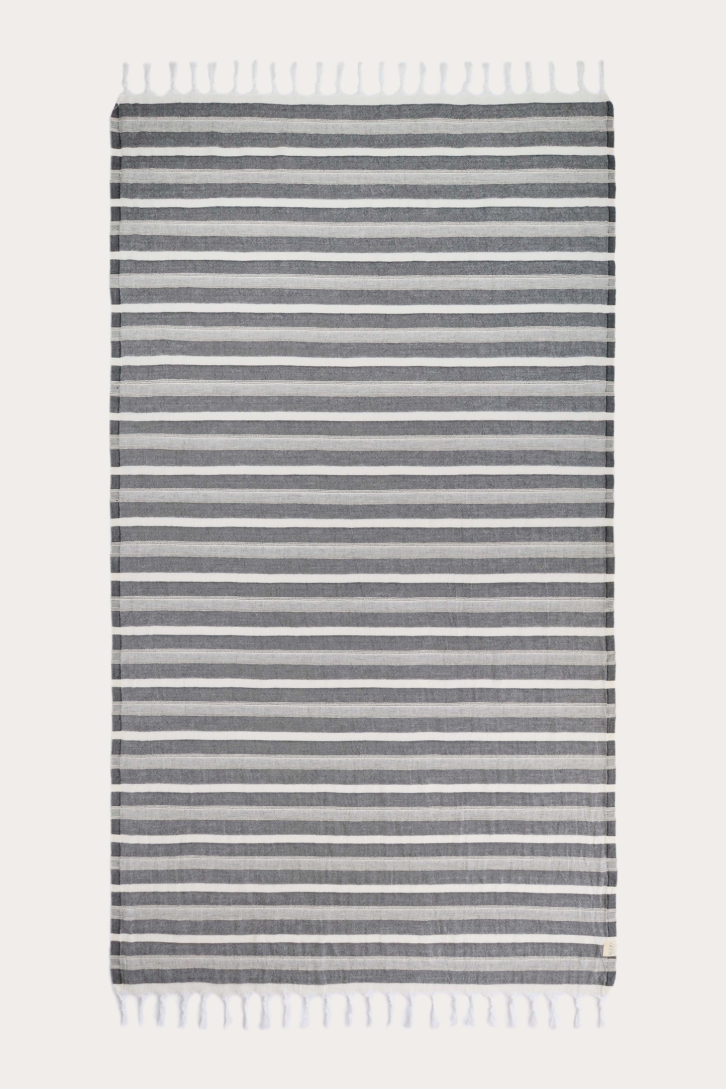 Avery Home Formentera black and white herringbone peshtemal laid flat, full view of quick-dry Turkish cotton hammam towel with tassel fringe, for beach, spa, and bath