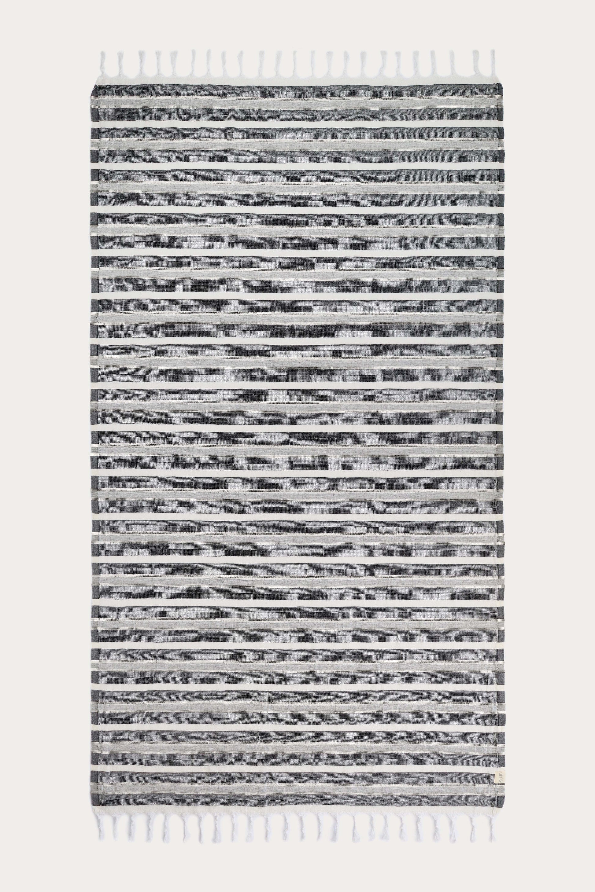 Avery Home Formentera black and white herringbone peshtemal laid flat, full view of quick-dry Turkish cotton hammam towel with tassel fringe, for beach, spa, and bath