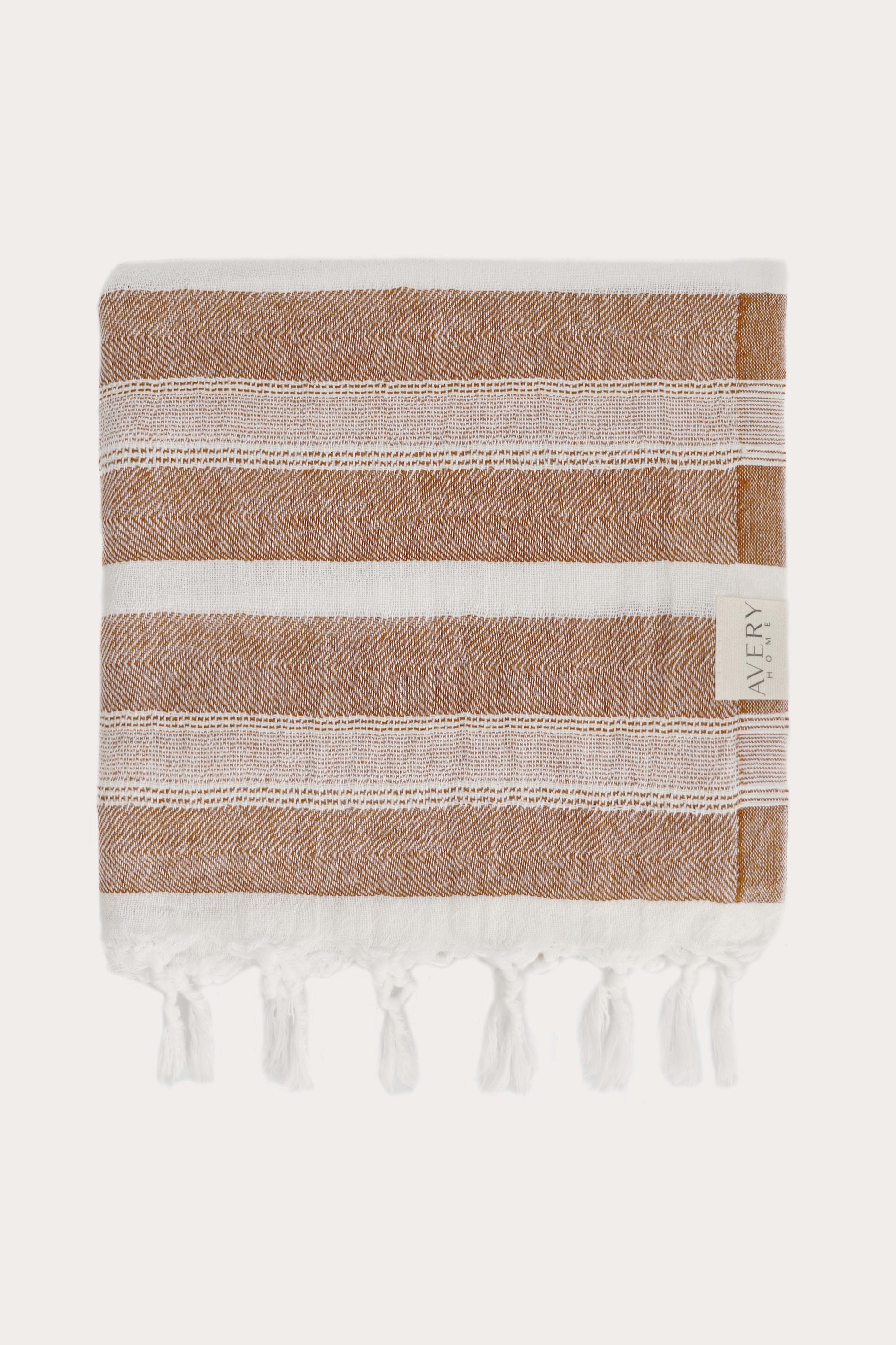 Avery Home Formentera peshtemal folded in terracotta herringbone weave, luxury Turkish hammam towel with hand-knotted tassel fringe, fast-drying and lightweight