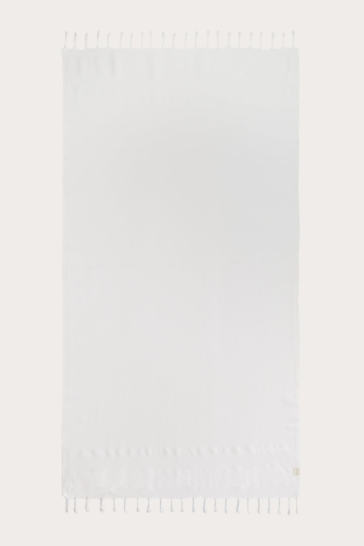 Avery Home white waffle weave peshtemal Turkish towel laid flat with hand-knotted tassel fringe, lightweight fast-drying luxurious spa towel