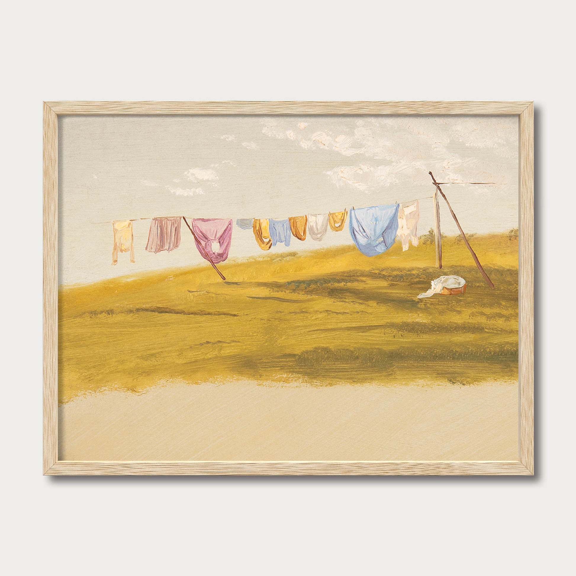 Cottagecore laundry room wall art in a natural oak frame featuring vintage countryside scenery with fresh laundry drying on a clothesline under an open sky