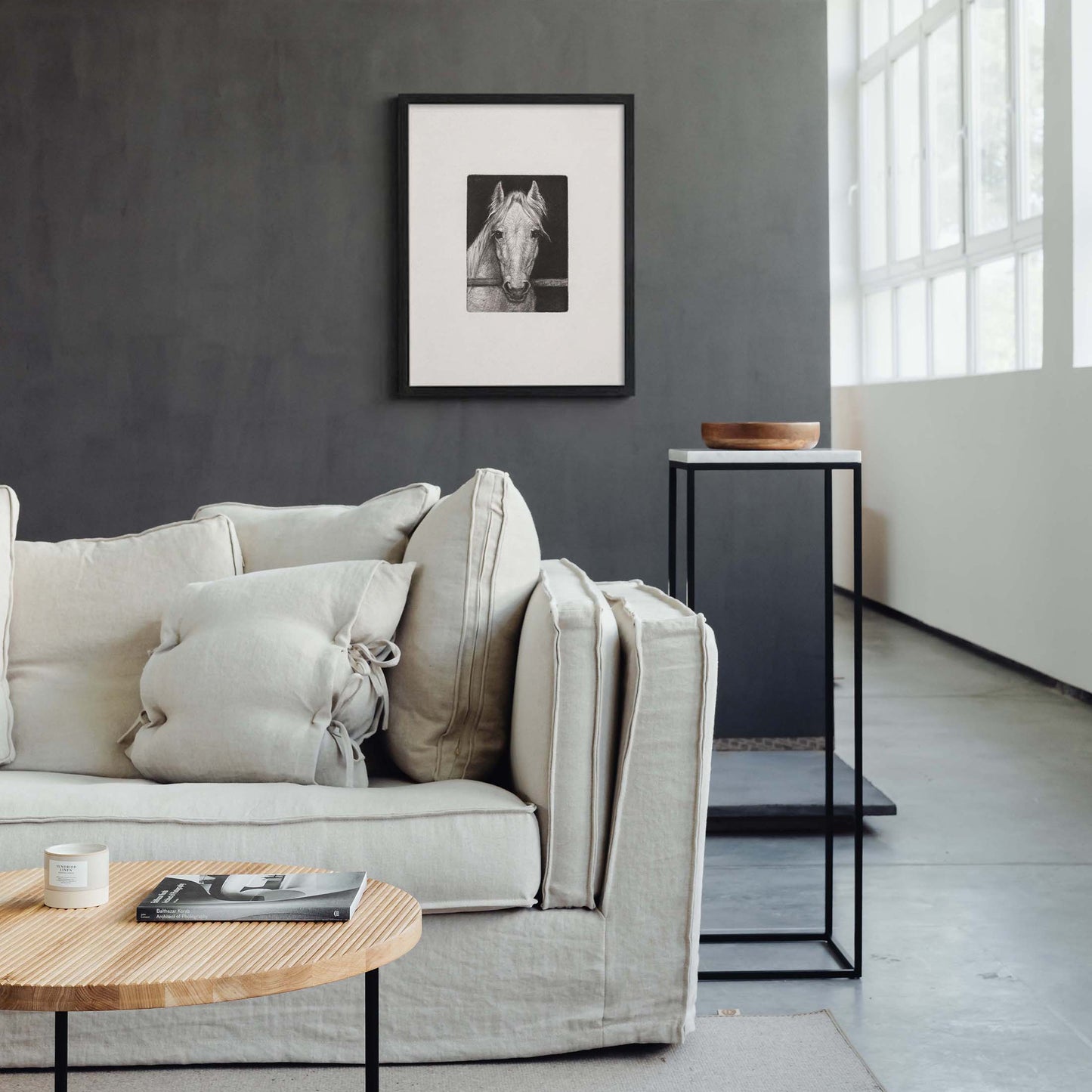 Black framed horse sketch wall art displayed above a neutral modern minimalist living room sofa