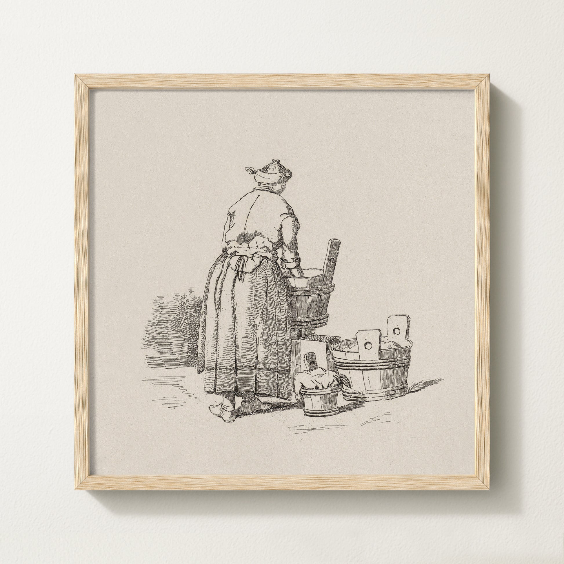 Framed vintage laundry sketch art print depicting a woman standing at wooden wash tubs in traditional attire.