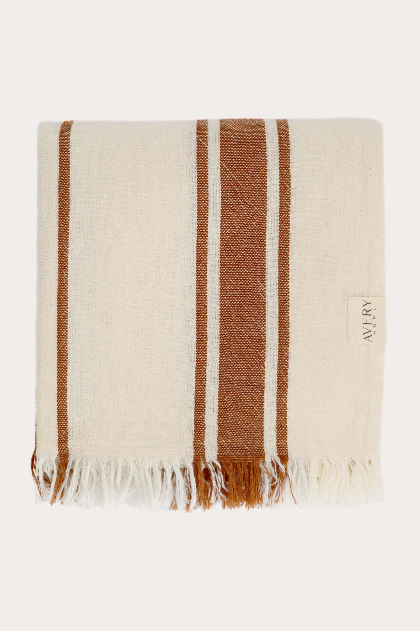 Folded orange and beige Amalfi Turkish towel in 100% cotton with cabana stripe pattern and fringe edges, midweight flat weave by Avery Home
