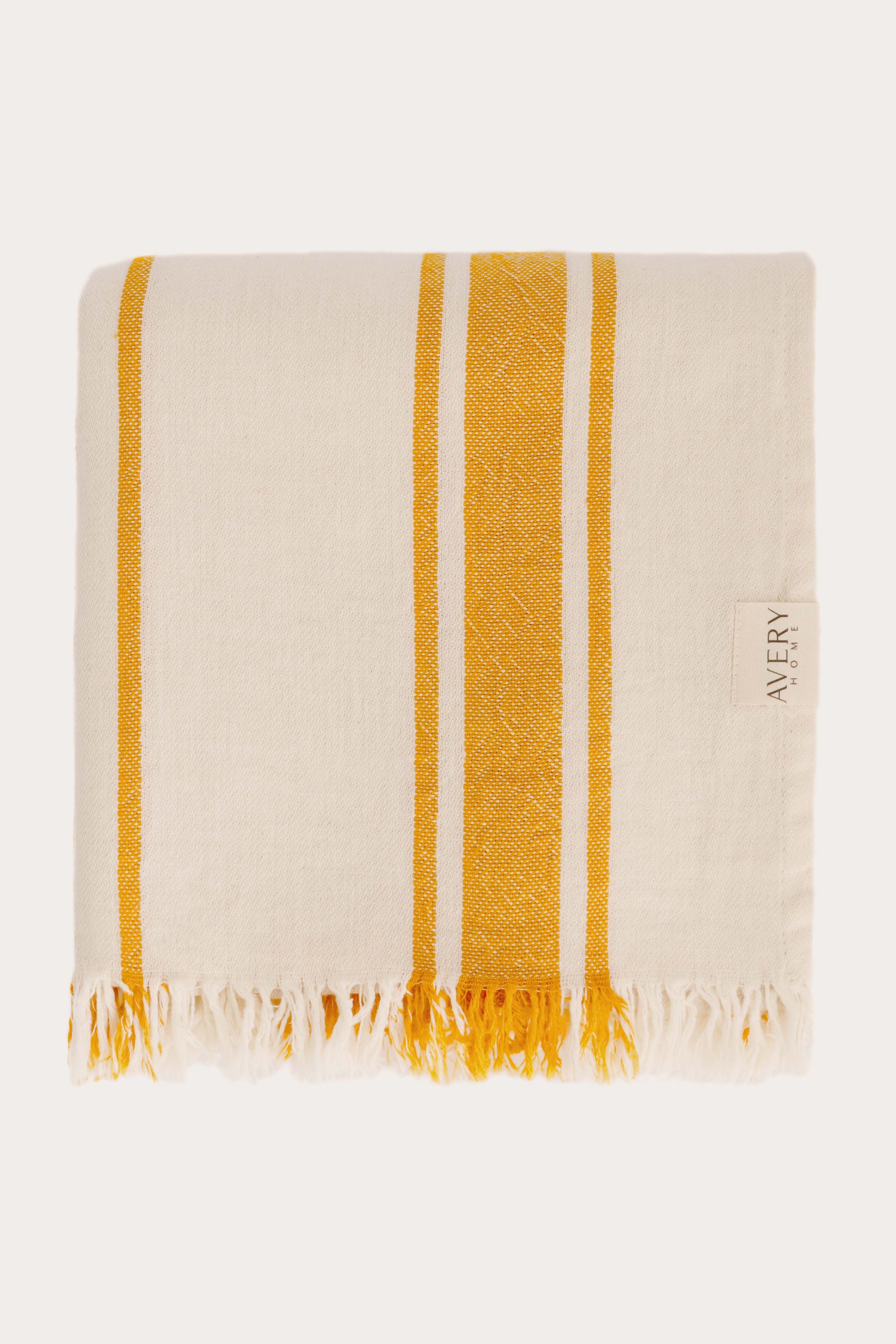 Folded yellow and beige Amalfi Turkish towel in 100% motton with cabana stripe pattern and fringe edges, midweight flat weave by Avery Home
